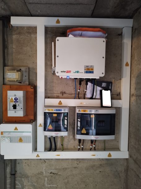 Panneau électrique avec plusieurs boîtiers et câblage sur un mur en béton.